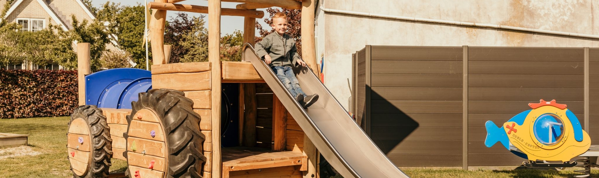 Kind glijdt van de glijbaan in de speeltuin van camping Kotestee in Ouddorp.